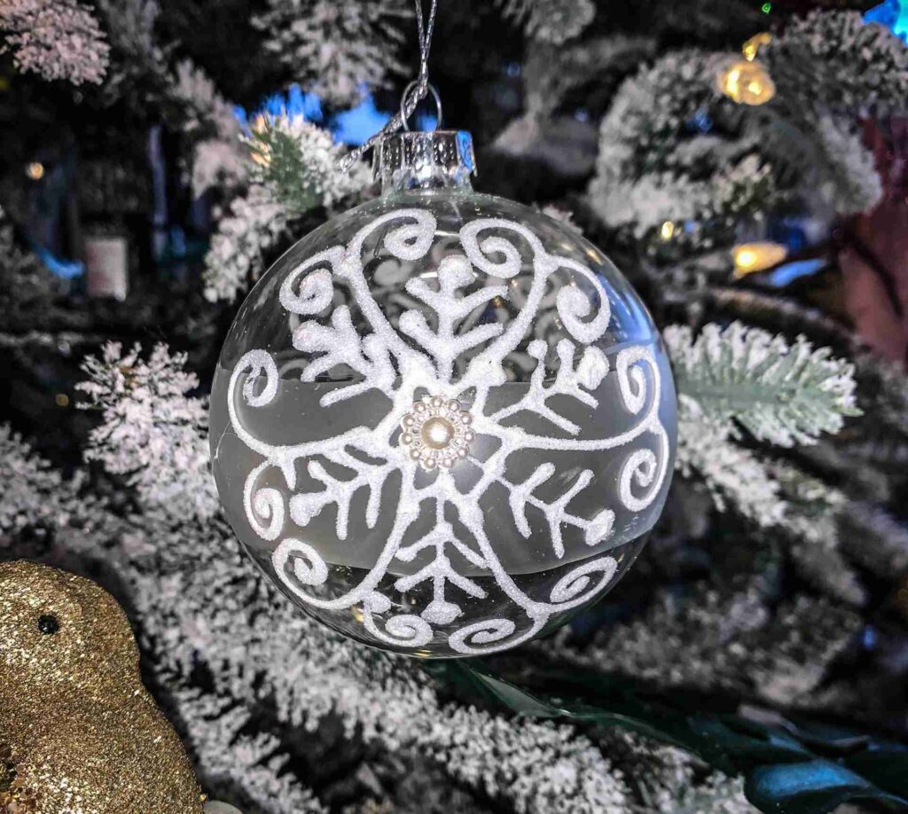 Set of 3 glass snowflake baubles with quirky christmas decorations on a christmas tree